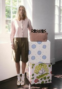 Prúžkovaná ružová a biela krátka blúzka s hnedým golierom, olivovo zelené kraťasy, žlté sandále a hromadené vzorované tašky na doplnky.
