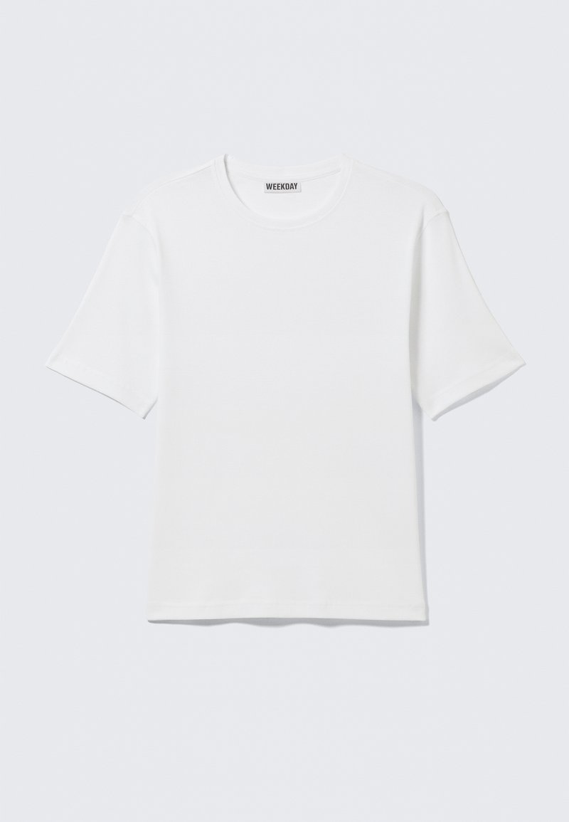 T-shirt blanc uni à manches courtes et col rond, avec une petite étiquette "WEEKDAY" à l'intérieur du col arrière, présenté à plat.