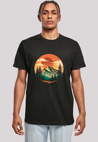 Black cotton t-shirt featuring a graphic design of mountains and trees against an orange and yellow circular sunset background.