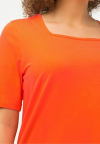 Top naranja de manga corta con escote cuadrado, textura suave y construcción sin costuras, diseñado para la comodidad y el uso casual.