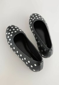 Melni ādas dzīvokļi apšūti ar baltām polka punktiem, ar apaļu purngalu un elastīgu zolī. Gluda tekstūra ar minimālām šuvju detaļām.