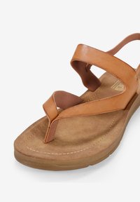 Sandalia de cuero marrón con dos correas anchas y un tope para los dedos. Plantilla texturizada y suela acolchada, con costuras decorativas a lo largo del borde.