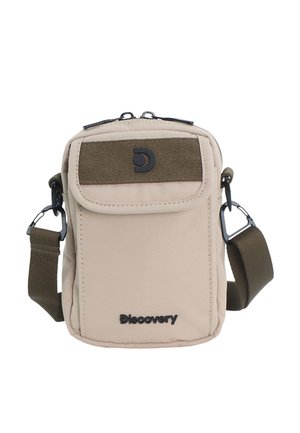 Beige compact crossbody bag with front flap pocket, adjustable olive strap, black Discovery logo, and zipper closure at top.