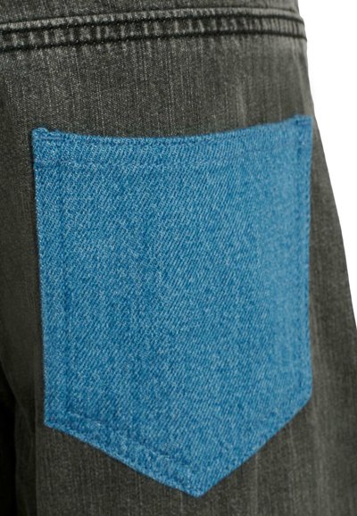 Tissu noir avec texture en denim gris, présentant une poche en denim bleu contrastante cousue à l'arrière. La poche a une forme rectangulaire.