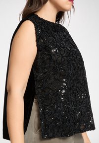 Czarny top bez rękawów z haftowanymi kwiatowymi wzorami z cekinami, teksturowanym dekoltem i zwiewną sylwetką. Uniwersalny na różne okazje.