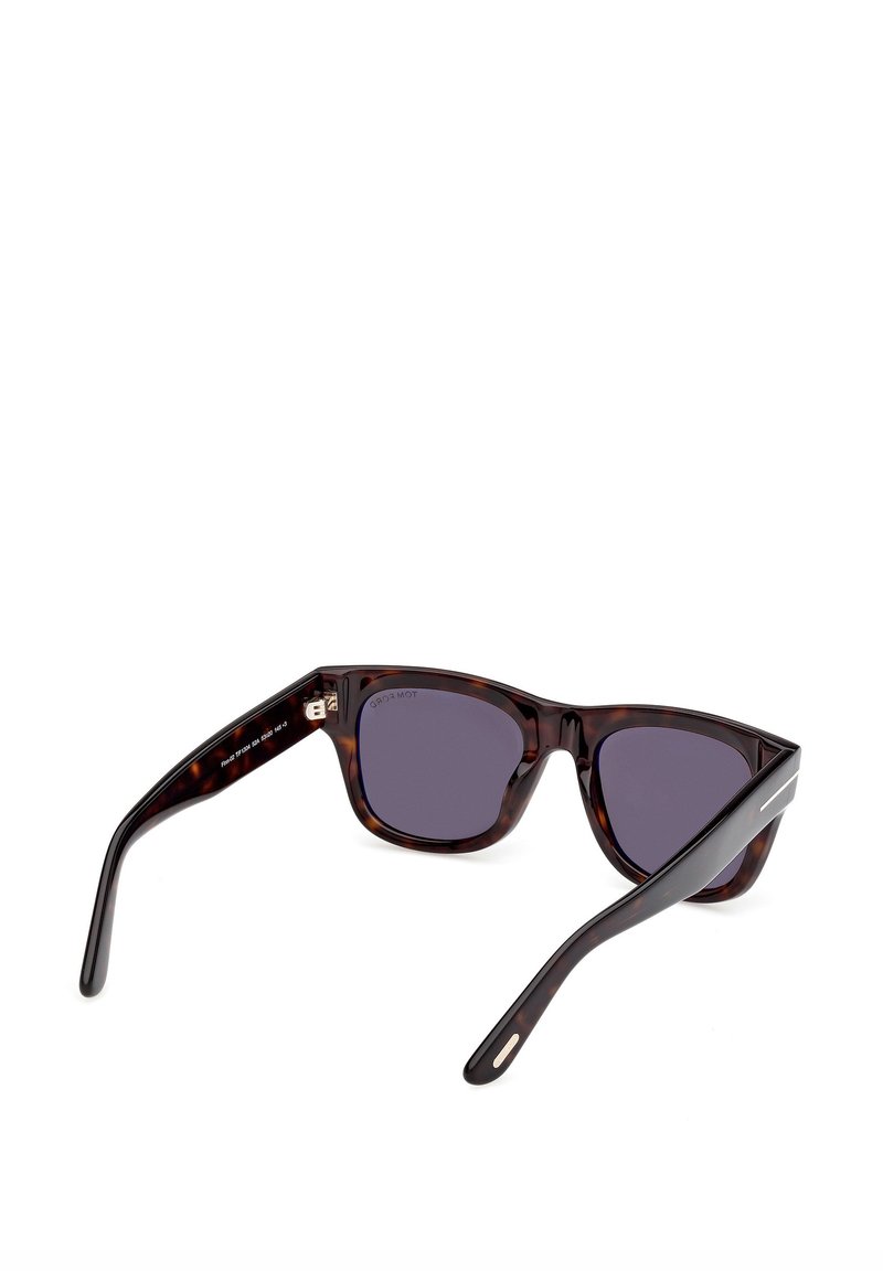 Lunettes de soleil écaille avec verres foncés. Elles présentent des branches larges et courbées ainsi que des accents métalliques subtils sur les tempes pour une touche moderne.