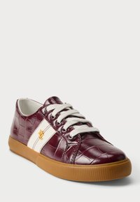 Μπορντό συνθετικά αθλητικά παπούτσια με υφή κροκοδείλου, λευκές ρίγες και χρυσό έμβλημα. Διαθέτουν επίπεδα λευκά κορδόνια και σόλα από καουτσούκ.