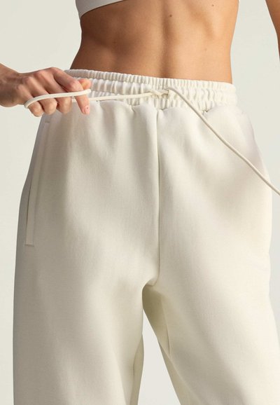 Crèmekleurige joggingbroek met een elastische tailleband en koord, voorzien van zijzakken en een zachte, gestructureerde stof.