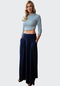Lichtblauwe ribgebreide cropped sweater gecombineerd met een marineblauwe maxirok met een geraffineerde tailleband en zijzakken, met een soepele textuur.