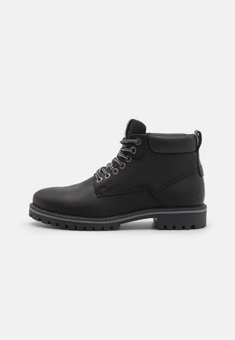 Bota de cuero negro hasta el tobillo con punta redonda, parte frontal con cordones, costura contrastante, tirador y suela de goma resistente con profundos surcos.
