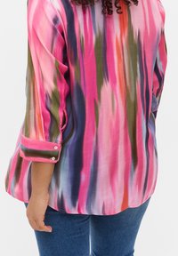 Blouse légère et colorée avec un motif tie-dye aux teintes rose, violet et vert. Poignets à boutons, coupe décontractée et texture fluide.