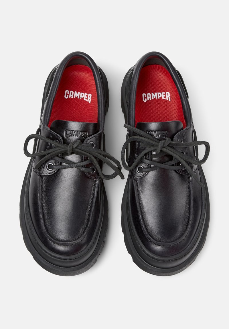 Sorte lædersko med runde tæer og tykke sorte gummisåler. Har sorte snørebånd og røde indersåler, mærket med "CAMPER."