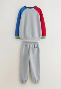 Šedá mikina s multicolorovými rukávmi (modrý, červený) a rebrovanými manžetami. Šedé tepláky s elastickým pásom a bočnou vreckom, z rovnakého materiálu.