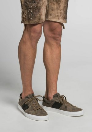 Bruine suède sneakers met donkere textielaccenten, ronde neus, witte rubberen zool en bruin veters, gecombineerd met lichtbruine shorts met borduursel.