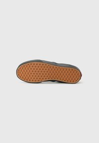 Semelle de sneaker noire avec un design en caoutchouc texturé, présentant un motif hexagonal et une zone de grip orange, complétée par des détails d'accent rouge.