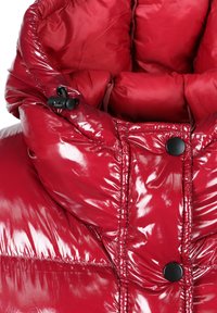 Błyszczący czerwony kołnierz kurtki puchowej z czarnymi zatrzaskami i regulowanym sznurkiem z zapięciem po lewej stronie.
