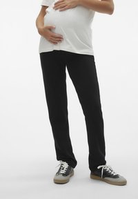 Svarta gravidbyxor i rak modell, gjorda av mjukt tyg. Kombineras med en vit t-shirt och avslappnade svarta och grå sneakers.