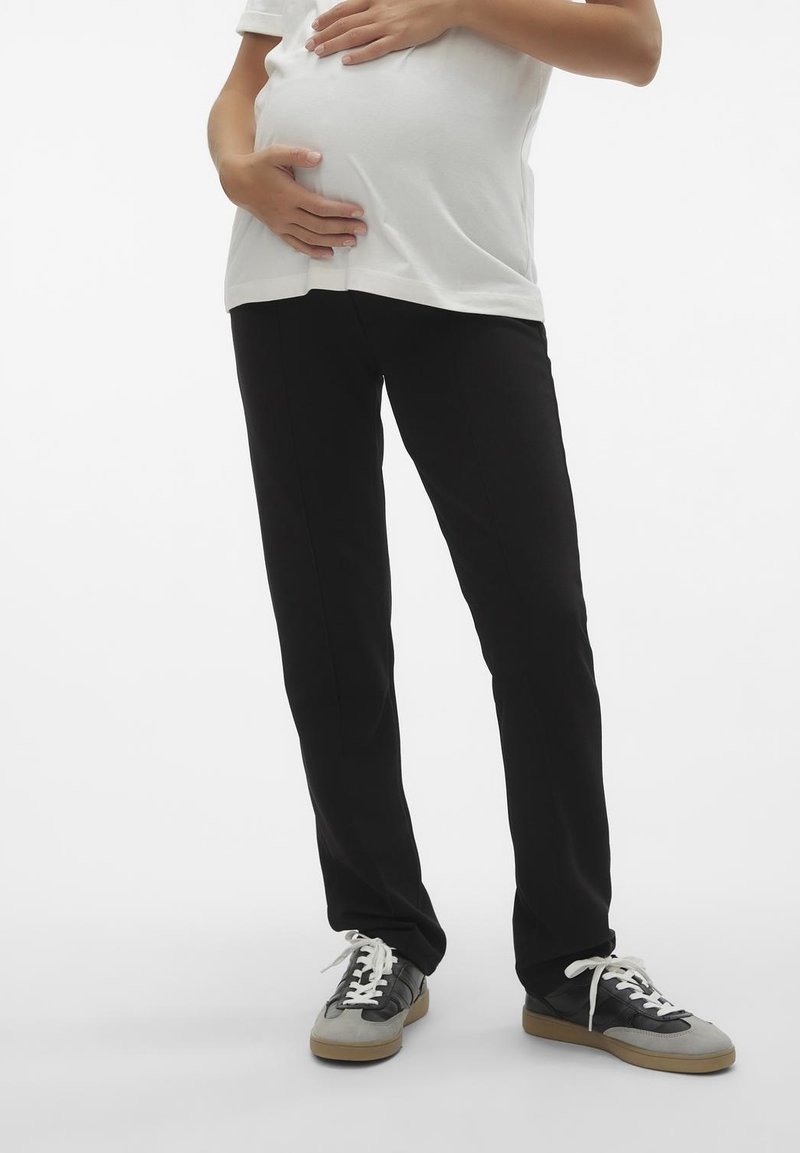 Svarta gravidbyxor i rak modell, gjorda av mjukt tyg. Kombineras med en vit t-shirt och avslappnade svarta och grå sneakers.