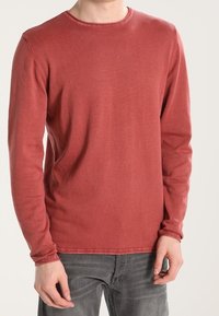 Maglia a maniche lunghe con scollo rotondo in rosso sbiadito, realizzata in morbido misto cotone. Presenta una vestibilità comoda e una texture sottile, con dettagli di cuciture visibili.