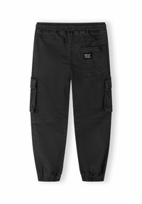 Un pantalon cargo noir présente une taille avec cordon de serrage, plusieurs poches latérales, des poignets élastiques et une petite étiquette sur la poche arrière.