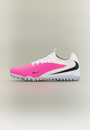 Chaussure de sport pour homme à coupe basse avec devant rose, talon blanc, logo Nike noir et semelle en caoutchouc texturée pour jouer sur gazon synthétique.