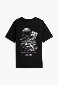 Μαύρο T-shirt με λευκό σχέδιο που απεικονίζει κράνος αγώνων, δύο αυτοκίνητα Formula 1, καρό σημαία, λογότυπο Cadillac και το κείμενο "Cadillac Formula 1 Team".