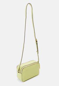 Sac bandoulière vert clair avec une forme rectangulaire structurée, deux compartiments zippés et une fine sangle ajustable avec des bords contrastés.
