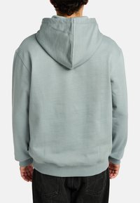 Lichtblauwe hoodie met een capuchon, geribde manchetten en zoom, met een zachte textuur en een losse pasvorm, gezien van achteren.