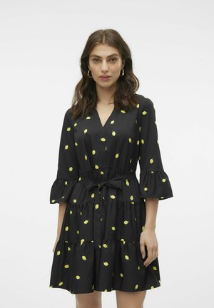 Robe noire avec imprimé citron, dotée d'un décolleté en V, d'une taille ceinturée, de manches évasées et d'un ourlet à volants en étages. Tissu lisse et design décontracté.
