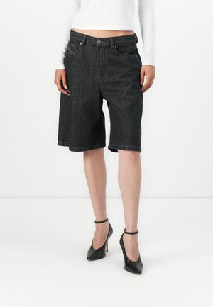 Svarte denimshorts med løs passform, oppbrett på kanten og framlommer. Kombinert med svarte ankelrem-hæler. Hvit langermet topp synlig.