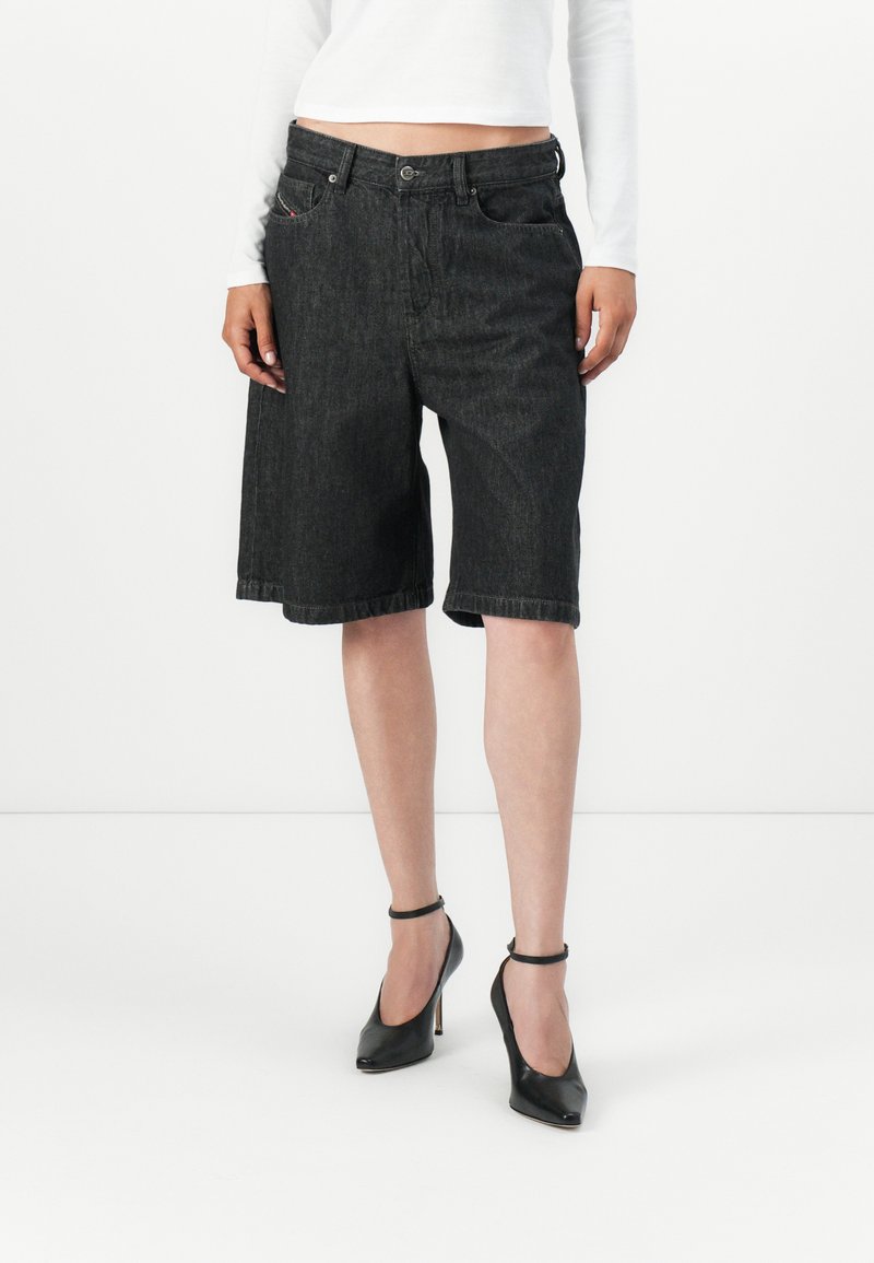Svarte denimshorts med løs passform, oppbrett på kanten og framlommer. Kombinert med svarte ankelrem-hæler. Hvit langermet topp synlig.