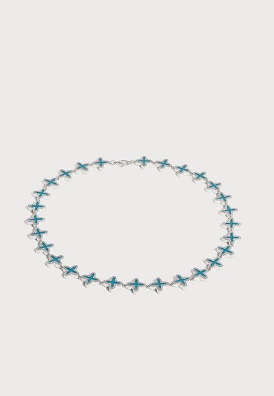 Collier en argent avec des breloques en forme de croix turquoise espacées régulièrement, reliées par de petites chaînes sur fond blanc.