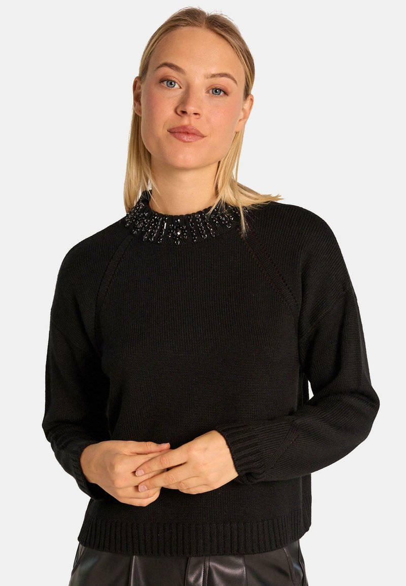 Czarny sweter z dzianiny z naszywanym dekoltem ozdobionym koralikami. Posiada ściągacz u dołu i na mankietach, luźny krój oraz fakturowany materiał.