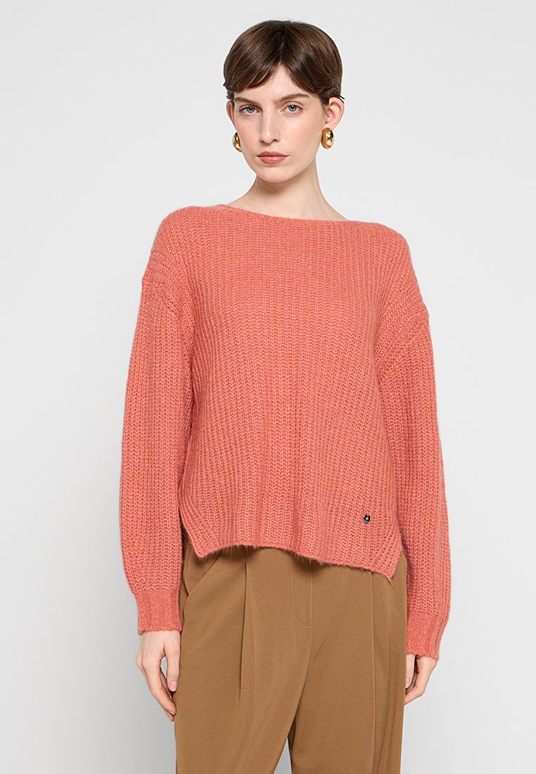 Maglione rosa a maglia con una vestibilità ampia, scollatura larga e polsini a coste. Fessure laterali notevoli e un piccolo dettaglio con logo all'orlo.