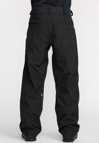 Pantalons de neige noirs à coupe ample, avec une ceinture, quatre poches, texture lisse et zones renforcées pour plus de durabilité.