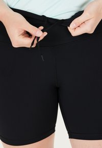 Svarta träningsshorts med en slät yta, med dragsko i midjan och platta sömmar för komfort och passform.