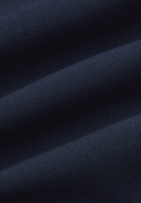 Granatowy materiał o gładkiej fakturze, z subtelnym połyskiem i delikatnymi falami, ukazujący wagę i elastyczność tkaniny.