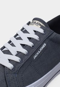 Ναυτικά μπλε αθλητικά παπούτσια Jack & Jones με λευκά κορδόνια, ραμμένες λεπτομέρειες και λευκή σόλα από καουτσούκ με μαύρη ρίγα.