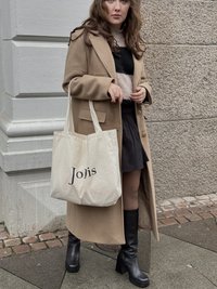Beige long coat, black sweater with stripes, black mini skirt, knee-high black boots, and a cream tote bag with "Joies" printed in black.