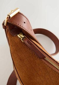 Bolso de mano de ante marrón con un patrón de rombos texturizado y un compartimento con cremallera con herrajes en tono dorado. Correa y detalles de piel.