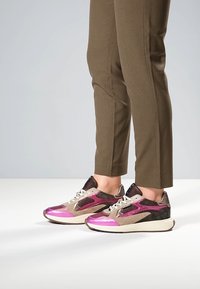 Baskets sportives avec un schéma de couleurs rose métallique et marron, accents en mesh, matériaux texturés, et une semelle amortie pour le confort.