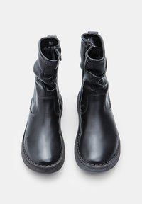 Bottines noires en cuir avec un design souple et décontracté, dotées de fermetures éclair latérales et de semelles en caoutchouc cousues pour la durabilité et l'adhérence.