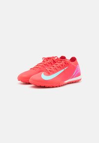 Red athletic shoes with a textured finish, featuring light blue accents and a purple design on the side. Lace-up closure with a curved sole.