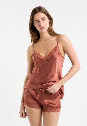Satinschlafset in einem warmen Terrakotta-Ton mit Spitzenakzenten, bestehend aus einem V-Ausschnitt-Camisole und Shorts mit Kordelzug. Durchgehend glatte Textur.