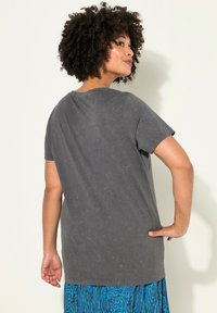 T-shirt gris à manches courtes en tissu doux, avec une coupe décontractée et un col rond, présentant une texture subtile et un détail de design au dos.