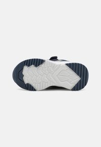 Sole di sneaker navy con gomma testurizzata in un motivo a zigzag. Presenta una resistente intersuola bianca e accenti blu scuro per una maggiore aderenza e stabilità.