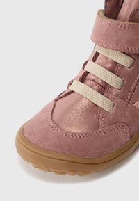 Roze nubuk i sjajni materijal čizme s tri bež elastične trake, gumeni potplat, zaobljeni vrh i podstavljenu podršku za gležanj.
