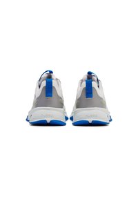 Scarpe da ginnastica grigie e bianche con accenti blu e suole testurizzate. Presentano un'etichetta sul tallone e un marchio sul lato.
