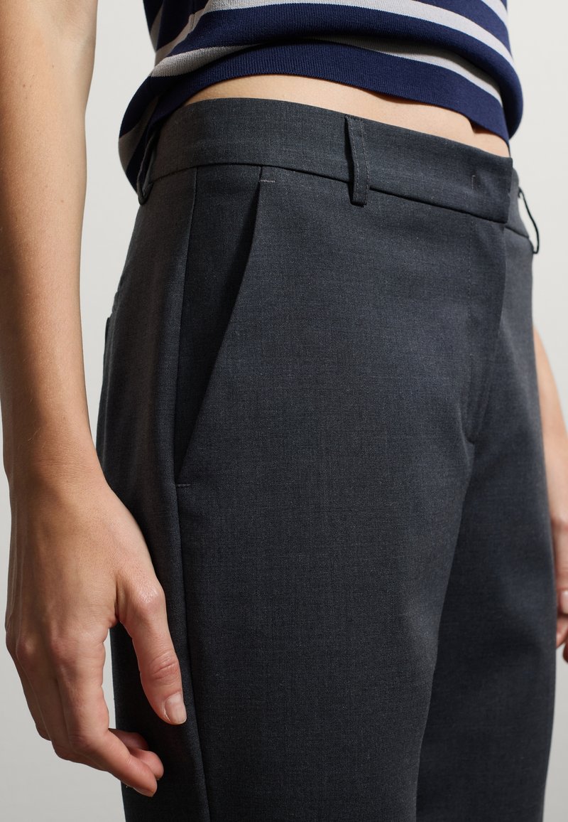 Grau maßgeschneiderte Hose mit glatter Textur, vorne mit Falten und seitlichen Taschen, ergänzt durch eine subtile Nahtdetail an der Taille.