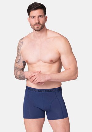 Navy blue boxer shorts with a black waistband featuring "MUCHACHOMALO" logo. Smooth fabric, fitted design, and standard length.